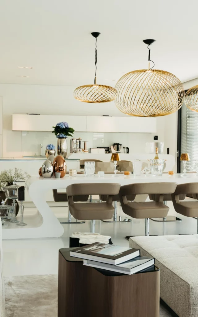 Eleganter Wohnbereich mit weißer Küche und opulentem Esstisch mit goldenen und beigen Akzenten