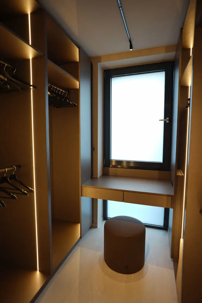 Luxuriöse Ankleide mit Schminktisch vor einem Fenster und Korpusse aus Cleaf, Sitzpouf in braun in Mainz Kizil Interior Services